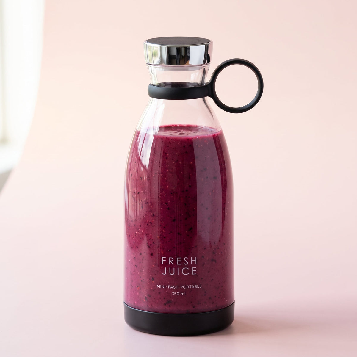 Swirlette portable blender in Black, filled with a berry smoothie, with a chrome lid and carry ring. [Black]