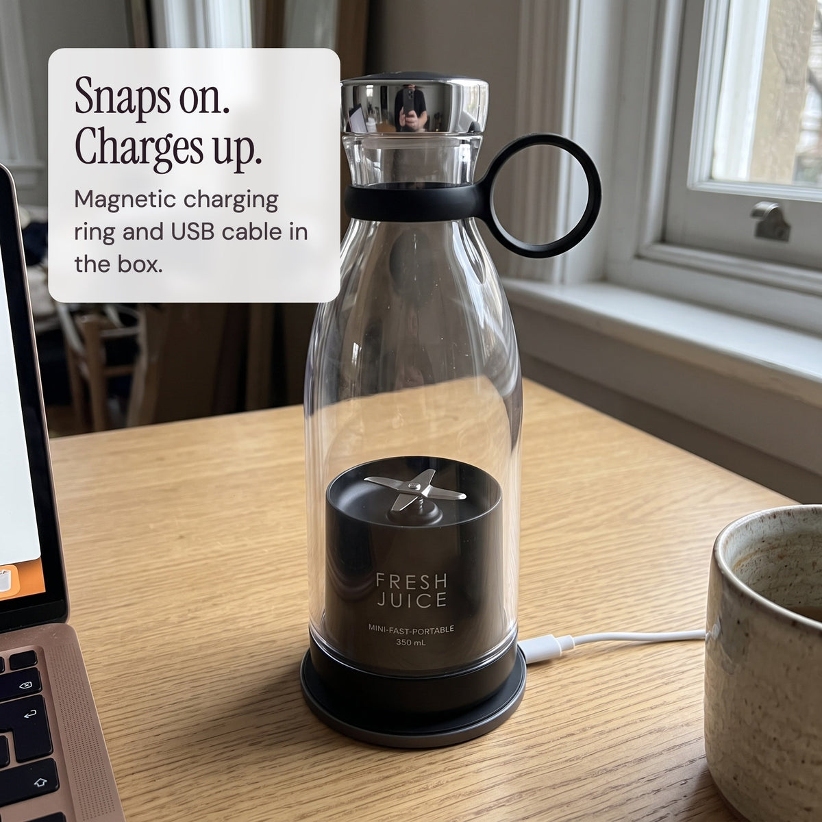 Black Swirlette charging on its magnetic charging ring on a desk.