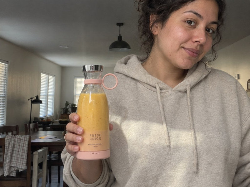Taylor holding a mango smoothie in her Swirlette in the kitchen.